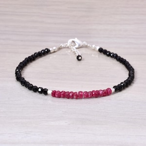 Op de afbeelding: Een delicate armband met zwarte en robijnrode kralen. De armband heeft een zilveren sluiting en is geregen op een dun, flexibel koord. De kralen zijn klein en facetgeslepen, wat een sprankelend effect creëert. Dit sieraad is geschikt voor dagelijks gebruik, ongeveer 18 cm lang.