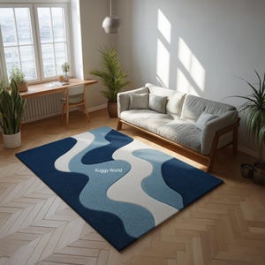 May include: A rectangular area rug with a wavy design in shades of blue and white. The rug is placed on a wooden floor in a living room setting, with a sofa and plants visible in the background. The text "Ruggy World" is visible on the rug.