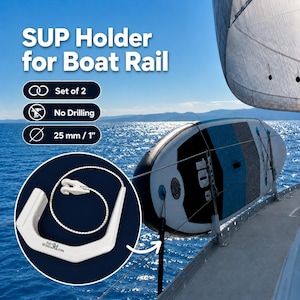 Könnte beinhalten: Ein weißer SUP-Halter für Bootsrelinge, im 2er-Set, ohne Bohren für 25 mm Relinge. Der Halter enthält ein weißes Bungee-Seil und ist mit FairWind3d.com beschriftet. Er ist montiert an einer Bootsreling mit einem Stand-Up-Paddleboard zu sehen.