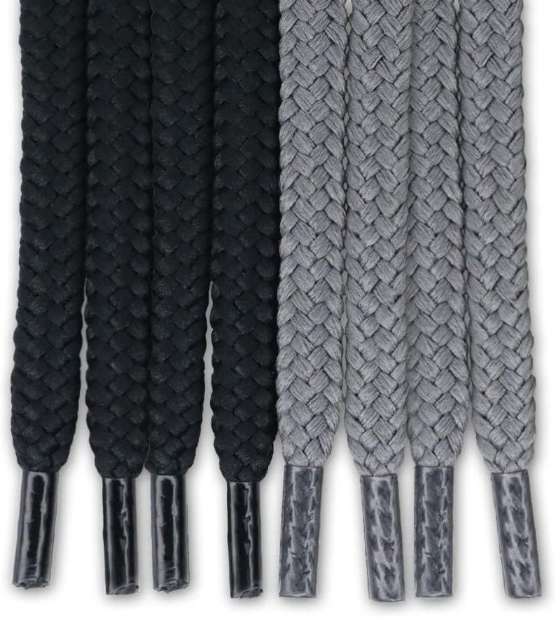 May include: A set of eight flat shoelaces arranged vertically, featuring four solid black laces and four solid gray laces. Each lace has a braided texture and is finished with a smooth, matching plastic aglet at the bottom end for durability.