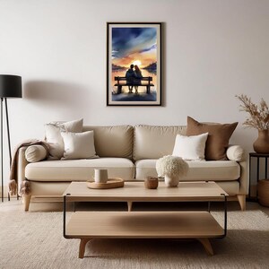 May include: A framed watercolour painting shows a couple on a bench, silhouetted against a sunset over a lake. The artwork uses blues, oranges, and yellows, creating a romantic and serene atmosphere. The painting is displayed above a beige sofa.