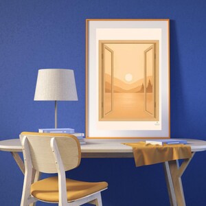 May include: An orange framed art print depicts a landscape scene viewed through an open window. The artwork features a sunset over a lake with mountains and trees. A desk lamp, chair, and books are in front of a blue wall.