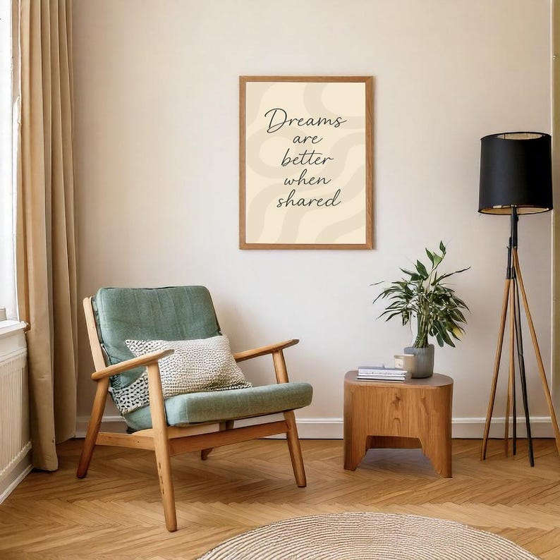 May include: A framed print with the text "Dreams are better when shared" hangs above a green armchair with a patterned pillow. A wooden side table holds a potted plant. A black lamp stands nearby.