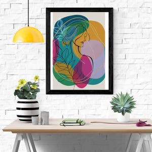 May include: Abstract art print in a black frame. The artwork features a minimalist line drawing of a woman's profile, overlaid with colorful shapes in teal, gold, pink, and green. Botanical elements are incorporated into the design.