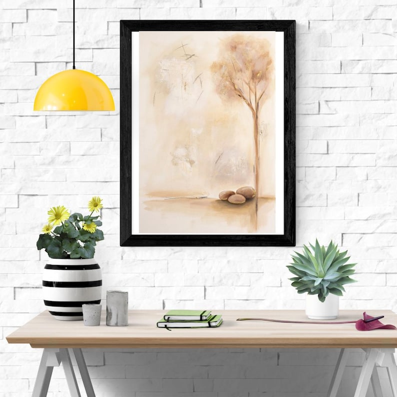 K&ouml;nnte beinhalten: Ein gerahmter Wandkunstdruck mit einem Aquarellgem&auml;lde eines einzelnen Baumes und drei glatten Steinen auf hellbeigem Hintergrund. Das Kunstwerk befindet sich in einem schlichten schwarzen Rahmen und zeigt weiche, neutrale Farbt&ouml;ne.