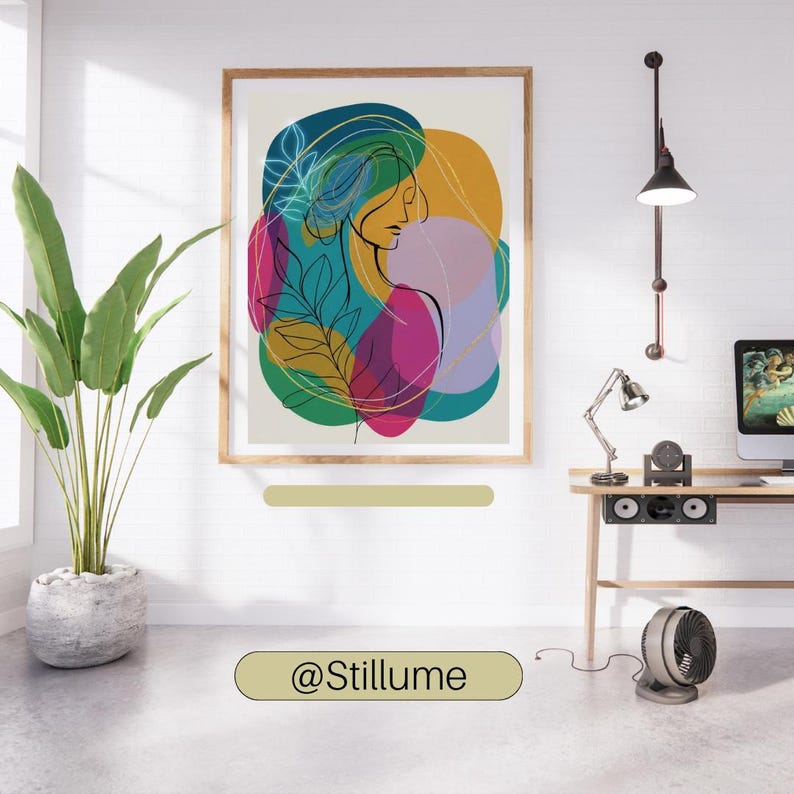 May include: Abstract art print featuring a woman's profile with colorful shapes and botanical elements. The artwork is framed in a light wood frame and hangs on a white brick wall. The print has a modern, minimalist aesthetic.