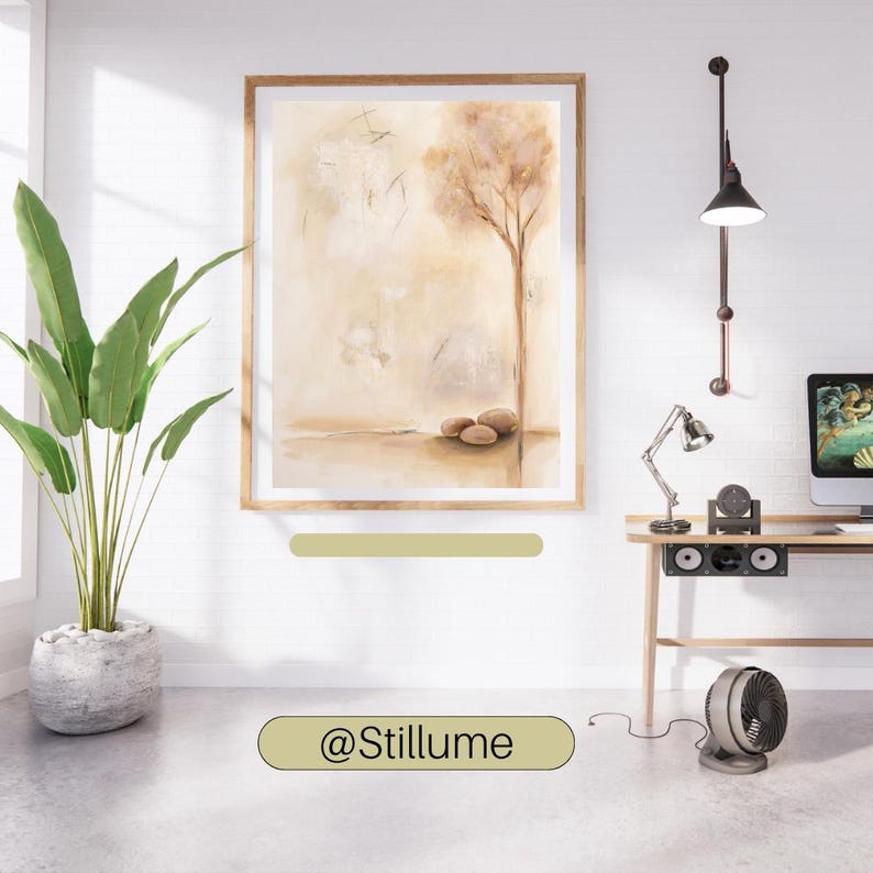 K&ouml;nnte beinhalten: Ein gerahmter Wandkunstdruck mit einer abstrakten Landschaft in Beige- und Braunt&ouml;nen, die einen einzelnen Baum und drei Steine am Boden zeigt. Das Bild h&auml;ngt an einer wei&szlig;en Wand neben einer gr&uuml;nen Topfpflanze, einer Schreibtischlampe und einem Monitor.