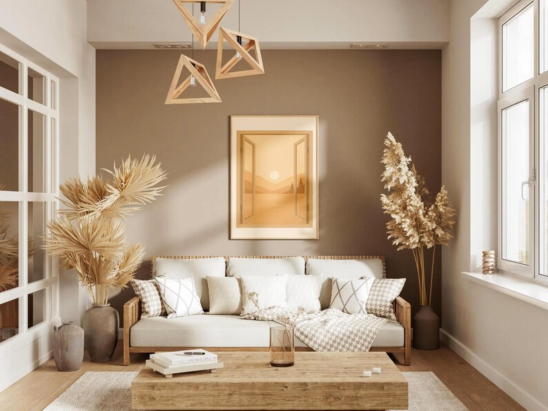 May include: A living room scene with a neutral color palette. A light-colored sofa with decorative pillows sits beneath a framed landscape painting. Wooden geometric pendant lights hang above a wooden coffee table.