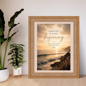 Może przedstawiać: Oprawiony wydruk ścienny przedstawiający zach&oacute;d słońca nad oceanem z tekstem "EVERY DAY IS A NEW beginning. TAKE A DEEP BREATH AND START AGAIN." Rama jest ozdobna, w kolorze złotym i teksturowana, otaczająca jasną ramkę typu passe-partout.