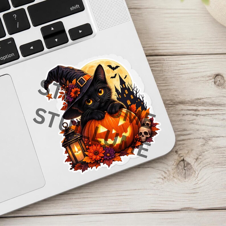 Op de afbeelding: Een gestanste sticker met een zwarte kat met een paarse heksenhoed, die zijn poten op een verlichte pompoen laat rusten. Het ontwerp bevat een gele volle maan, een donker kasteelsilhouet, vleermuizen, herfstbladeren en een schedel.