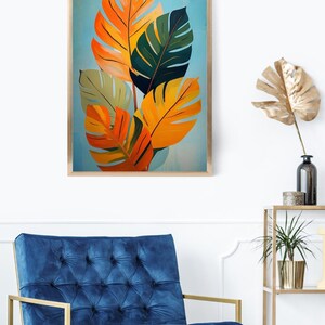 Pu&ograve; includere: Una stampa artistica botanica incorniciata con foglie tropicali stilizzate nei toni dell'arancione, giallo e verde su uno sfondo azzurro. L'opera d'arte &egrave; in una cornice di legno. L'immagine &egrave; esposta in una stanza con una poltrona di velluto blu.