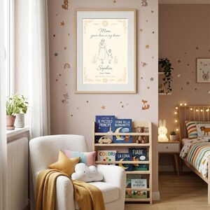 May include: A framed print with the text "Mom, your love is my home" and the name "Sophia". The artwork depicts a mother and child. The room has a white armchair, a bookshelf with children's books, and decorative wall stickers.