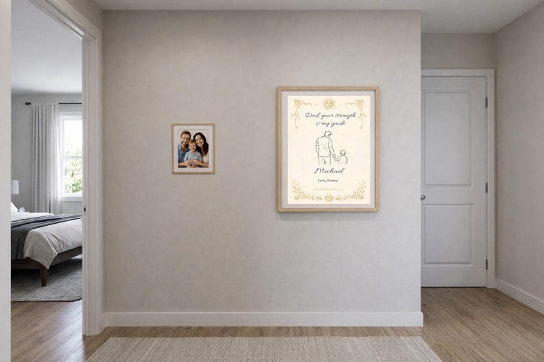 K&ouml;nnte beinhalten: Zwei gerahmte Drucke h&auml;ngen an einer hellgrauen Wand. Einer ist ein Familienportr&auml;t, der andere zeigt eine Strichzeichnung eines Vaters und Kindes mit dem Text "Papa, deine St&auml;rke ist mein Wegweiser" und dem Namen "Michael".