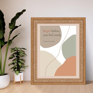 K&ouml;nnte beinhalten: Ein gerahmter Kunstdruck mit abstrakten organischen Formen in gedeckten T&ouml;nen von Beige, Salbeigr&uuml;n und Terrakotta. Der Text lautet: "Begin before you feel ready. Courage starts quietly." Der Rahmen ist goldfarben, verziert und weist eine Perlenstruktur auf.