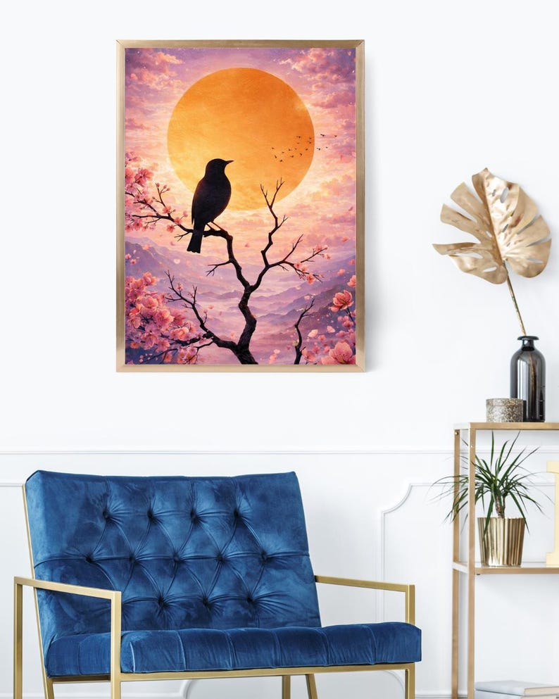 Pu&ograve; includere: Una stampa artistica incorniciata raffigurante un uccello nero posato su un ramo, sullo sfondo di un tramonto con un grande sole arancione. Fiori di ciliegio rosa e montagne viola arricchiscono la scena. L'opera &egrave; esposta in una stanza con una poltrona blu.