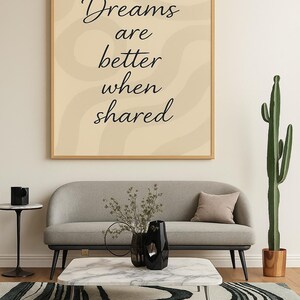 May include: A living room scene featuring a framed print with the text "Dreams are better when shared." A gray sofa, marble coffee table, and patterned rug are in front of a white wall. A tall cactus and black vase complete the decor.