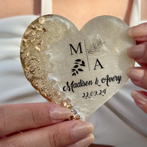 May include: Heart-shaped coaster with a gold leaf design and the names "Madison & Avery" with the date "22.09.24" printed in black. The coaster has a white and gold color scheme.