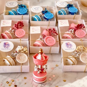 May include: A collection of square white gift boxes containing miniature carousel music boxes, each adorned with dried flowers and a wax seal stamped with the words Thank You. A single pink and white carousel music box stands in the foreground.