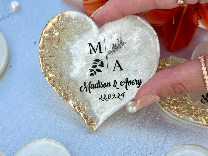 May include: Heart-shaped decorative item with gold leaf edging and a white center. The center features the initials "MA" with botanical accents and the names "Madison & Avery" with the date "22.09.24".