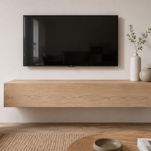 May include: A rectangular light oak wood floating media console mounted on a wall beneath a large flat-screen television. Two ceramic vases, one tall and cylindrical and one short and rounded, sit on the right side of the console top.