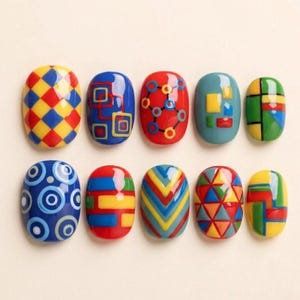 May include: A collection of ten colorful, oval-shaped nail art designs. Each nail features a unique geometric pattern in vibrant colors like red, blue, yellow, and green. Designs include squares, circles, and chevron patterns, creating a playful and artistic aesthetic.