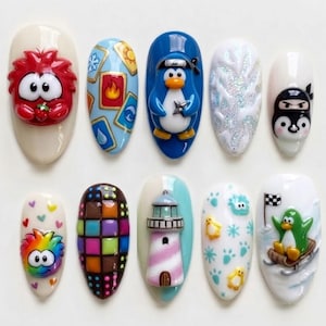 May include: A set of ten press-on nails featuring 3D designs including a red creature, elemental cards, a blue ninja penguin, white glitter texture, a black ninja face, a rainbow creature, a colorful grid, a lighthouse, and a sledding penguin.