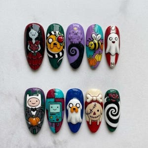 May include: A set of ten almond-shaped press-on nails featuring 3D relief designs of various cartoon characters and Halloween-themed motifs, including a vampire, a dog, a ghost, a bee, pumpkins, a robot, and a spiral pattern in vibrant colors.