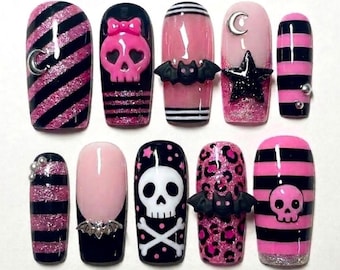 May include: A set of ten artificial nails in a gothic theme. Designs include pink and black stripes, skulls, bats, moons, stars, and leopard print. Some nails have 3D embellishments. The nails are in various shapes, including oval and coffin.