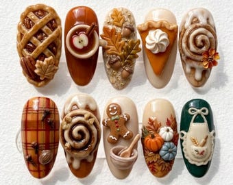 May include: A set of ten press-on nails featuring 3D autumn-themed designs including a pecan pie, apple cider, fall leaves, pumpkin pie, cinnamon rolls, plaid patterns, a gingerbread man, pumpkins, and a white apron on a dark green background.