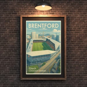 May include: A framed art print featuring the Brentford Gtech Community Stadium. The print has a vintage travel poster style with the word "Brentford" at the top. The stadium is depicted with a green field and surrounding buildings.