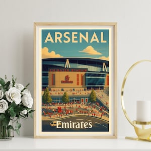 May include: A framed art print featuring the Emirates Stadium, home of Arsenal Football Club. The artwork has a vintage travel poster style, with the word "ARSENAL" at the top and "Emirates" at the bottom. The stadium is depicted with a crowd of people.