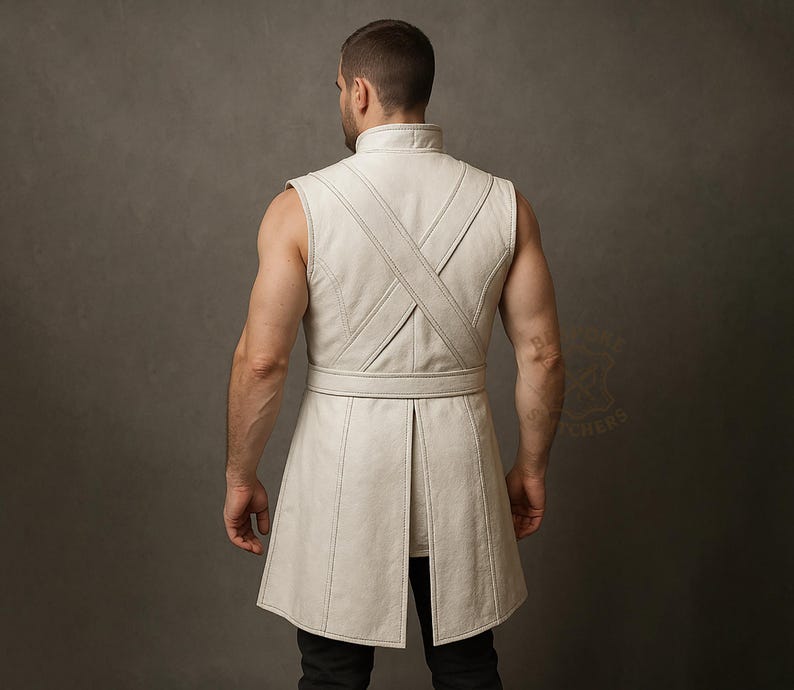 May include: A sleeveless, off-white leather tunic with a high collar and a belted waist. The tunic features a cross-stitch design on the back and a split hem. The garment is worn over black pants.