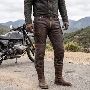 May include: Dark brown leather cargo trousers featuring a front zip fastening, side utility pockets, and ribbed detailing above the knees. The trousers are paired with matching brown leather boots and brown leather gloves, worn with a dark jacket.