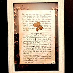 Seite aus einem Gebetbuch mit gepresstem vierblättrigen Kleeblatt. Im hellen Holzrahmen oder im schwarzen Rahmen.