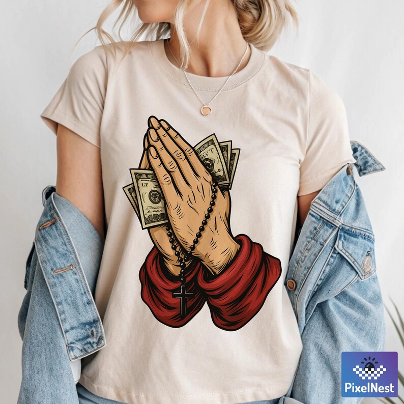 Pu&ograve; includere: T-shirt beige con una grafica di mani in preghiera che tengono soldi e un rosario con una croce. Le mani sono illustrate in dettaglio, con i soldi visibili tra i palmi. Le maniche sono rosse.