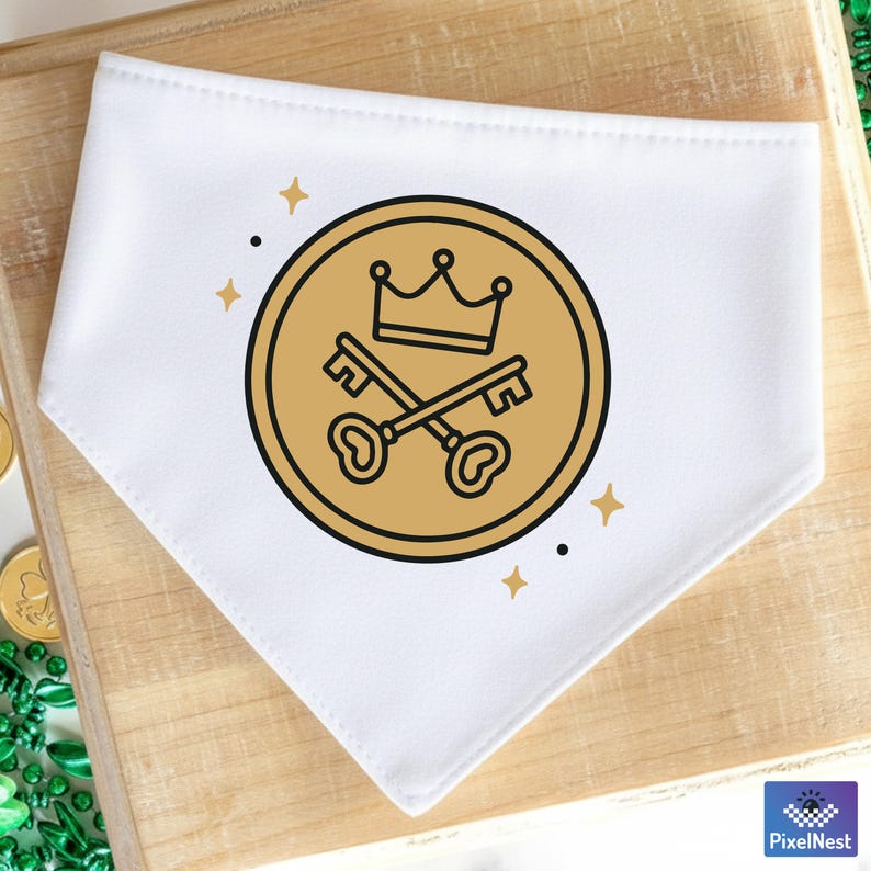 May include: White dog bandana with a gold coin design featuring a crown and crossed keys. The design is surrounded by small gold stars and black dots. The bandana is made of a soft, white fabric.