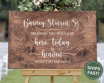 May include: A wooden sign with the text "Barney Stinson, Sr. We know you would be here today if heaven wasn't so far away." The sign is displayed on a wooden easel, with flowers at the top.