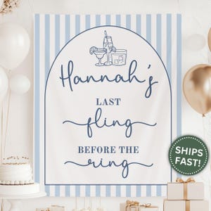 May include: A sign with blue and white stripes and the text "Hannah's Last Fling Before the Ring" in a script font. The sign has an arched border and illustrations of cocktails. White and gold balloons are in the background.