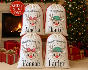 May include: Four white Christmas gift bags with red trim and drawstring closures. Each bag features a reindeer graphic with a red bow or green cap, and a name. The text "Merry Christmas" and "Special Delivery For" are also printed on the bags.