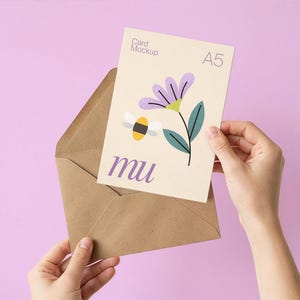 May include: A5 card mockup with a floral and bee illustration, held in a brown envelope. The card features a purple flower, green leaves, and a yellow and black bee. The word "mu" is printed on the card.