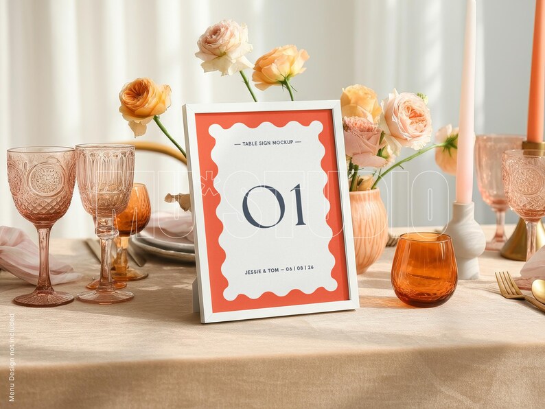 Pu&ograve; includere: Un'apparecchiatura con un segnaposto con cornice bianca con il numero "01". Il segnaposto ha un bordo corallo ed &egrave; circondato da vetreria, fiori e candele. La tavola &egrave; apparecchiata per un evento speciale.