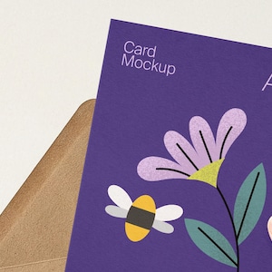 May include: A purple A5 card mockup with a floral and bee illustration. The card has the text "Card Mockup" and "A5" printed on it. The card is partially inserted into a brown envelope.