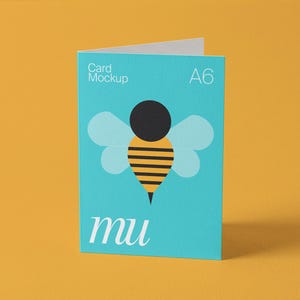 Pu&ograve; includere: Mockup di biglietto A6 turchese con un'illustrazione di un'ape. L'ape ha una testa nera, un corpo a strisce gialle e nere e ali azzurre. La carta mostra "Card Mockup" e "mu" in bianco, su sfondo giallo.