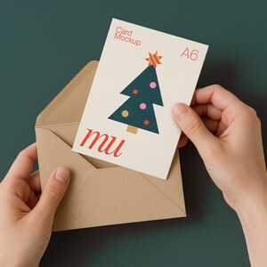 May include: A6 card mockup with a Christmas tree design, held in a brown envelope. The card features a green tree with pink and yellow ornaments and a red star. The text "Card Mockup" and "mu" are also visible.