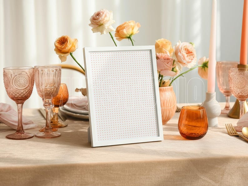 Pu&ograve; includere: Una lavagna bianca con cornice &egrave; appoggiata su un tavolo apparecchiato per un'occasione speciale. Il tavolo &egrave; adornato con bicchieri rosa, candele e un vaso di rose. Un bicchiere arancione &egrave; vicino alla lavagna.
