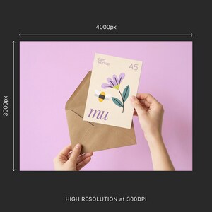 May include: A5 card mockup with a floral and bee illustration, held in a brown envelope against a light purple background. The card features a purple flower, green leaves, and the word "mu".