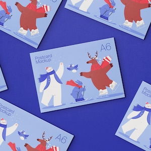 Peut inclure: Une collection de cartes postales A6 sur fond bleu clair illustrées d'un ours blanc, d'un renne brun et d'un lapin bleu portant des écharpes et des accessoires d'hiver. Le texte Postcard Mockup et A6 est imprimé sur chaque carte.