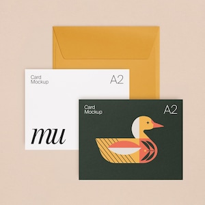 Pode incluir: Um envelope amarelo mostarda com dois cartões A2. Um cartão é branco com o texto Card Mockup, A2 e mu. O segundo cartão é verde escuro com o texto Card Mockup, A2 e um gráfico estilizado de um pato em amarelo, laranja e branco.