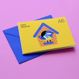 Op de afbeelding: Een gele A6-kaart met een vogelhuisillustratie en de tekst "Card Mockup" en "A6" ligt op een blauwe envelop. Het vogelhuisje heeft een blauwe vogel en een stippenpatroon. De achtergrond is effen paars.