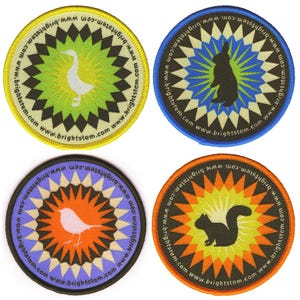 May include: Four circular embroidered patches with animal designs. Each patch features a central animal image: a goose, a rabbit, a bird, and a squirrel. The patches have a geometric starburst design in various colours and the text "www.brightstem.com" around the edge.